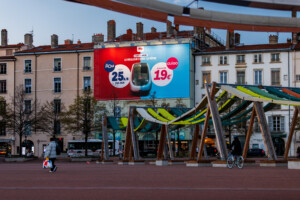 Toile publicitaire sur échafaudage de 180 m² pour la SNCF, vue de face illuminée de nuit au cœur de Lyon.