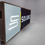 Caisson lumineux LightBox grue latérale, toile backlit recto verso, logo SOLUDEC, posé sur fond gris
