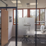 Vitrophanie en film dépoli ajouré assurant la confidentialité des bureaux, intégrée à la signalétique d'agence bancaire à Bourg-en-Bresse.