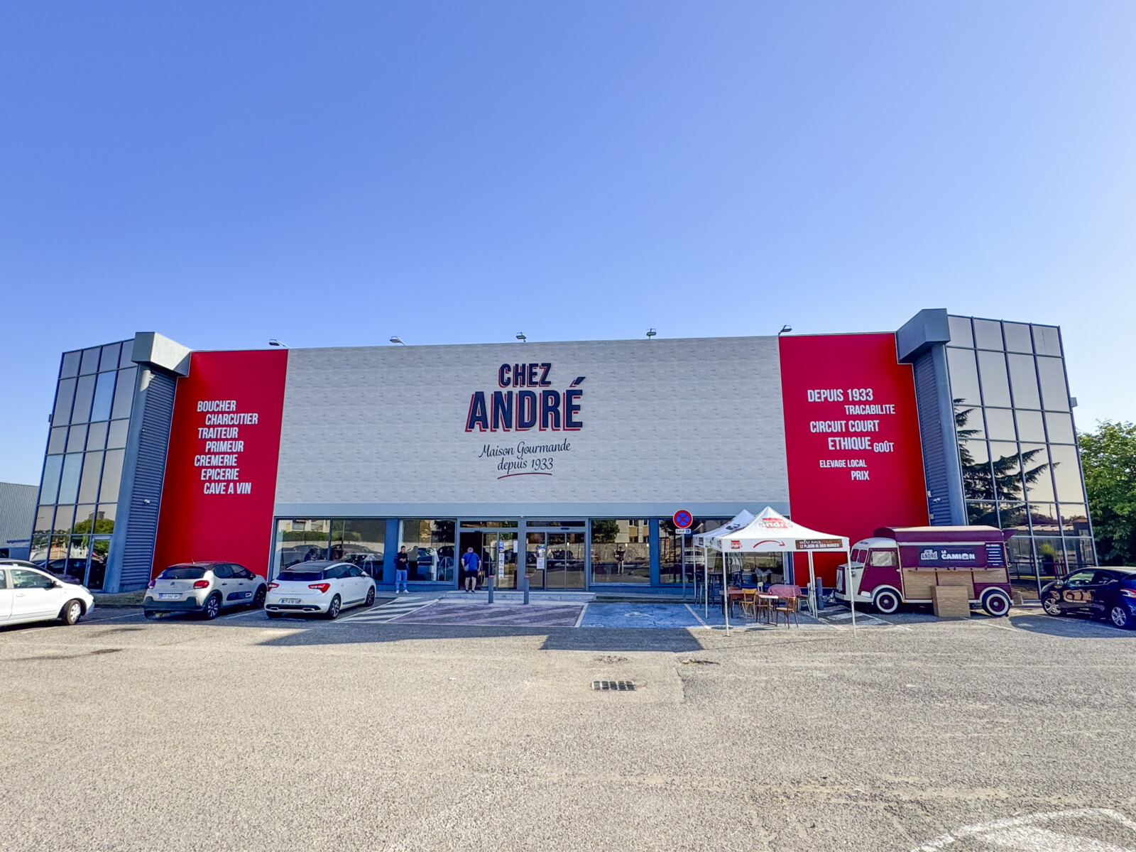 Façade extérieure avec toile Slimbox effet briques et lettres boîtiers installée par LightAir à Saint Bonnet de Mure pour le déploiement d'enseignes multi-sites des Boucheries André.