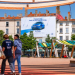 Vue de face en plein jour du dispositif Volkswagen aidant à financer les travaux de façade sur la place Bellecour à Lyon.