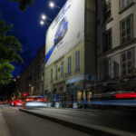 Vue nocturne de côté de l'affichage XXL finançant la rénovation de façade, avec la circulation adjacente à la place Bellecour.