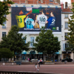Vue lointaine de jour de face illustrant l'intégration urbaine parfaite de cette campagne grand format au cœur de Lyon, sur la place Bellecour.