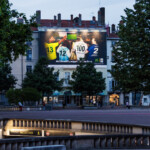 Superbe vue lointaine de nuit de face mettant en lumière la campagne grand format McDonald's sur la place Bellecour à Lyon.