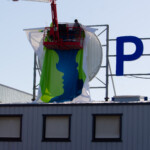 Technicien installant la toile tendue d'une enseigne façade nouvelle génération en hauteur.