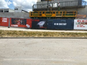 Palissade de chantier en toile imprimée avec slogans sur l'esprit d'équipe et la passion.