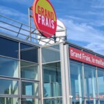 Enseigne ronde Grand Frais à impression numérique recto-verso installée en hauteur.