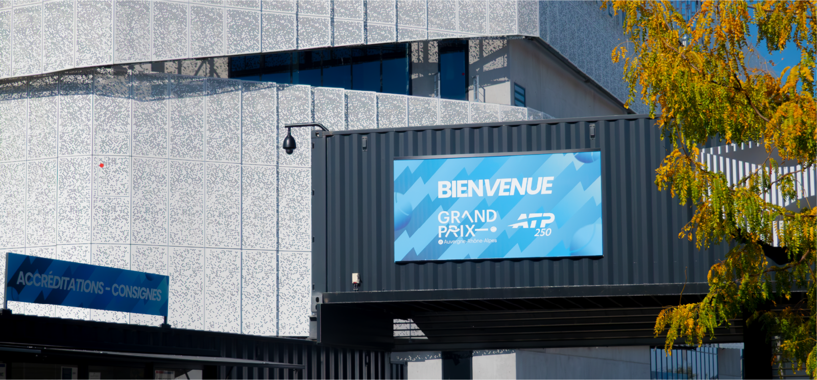 Entrée extérieure avec bannières d'accueil et signalétique événementielle à Lyon devant le complexe sportif.