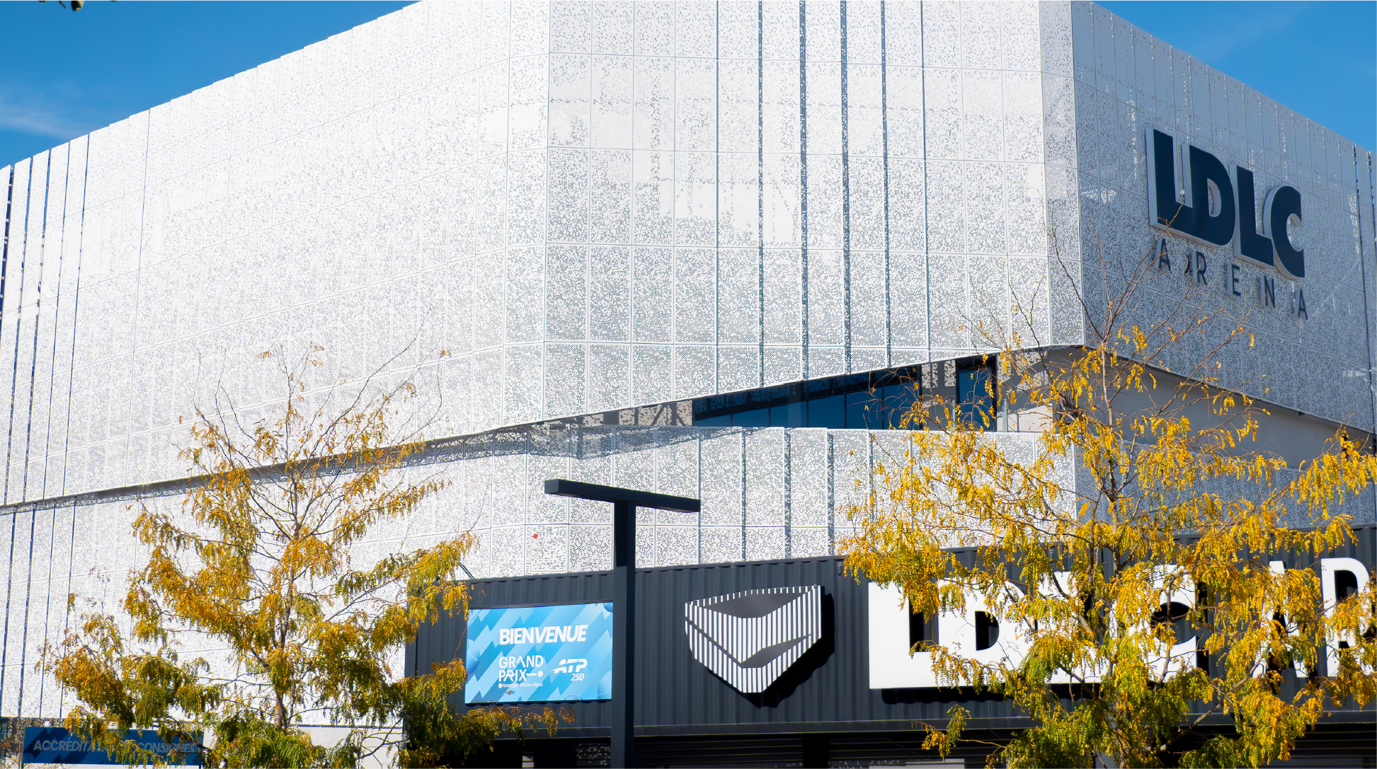 Entrée extérieure avec bannières d'accueil et signalétique événementielle à Lyon devant le complexe sportif.